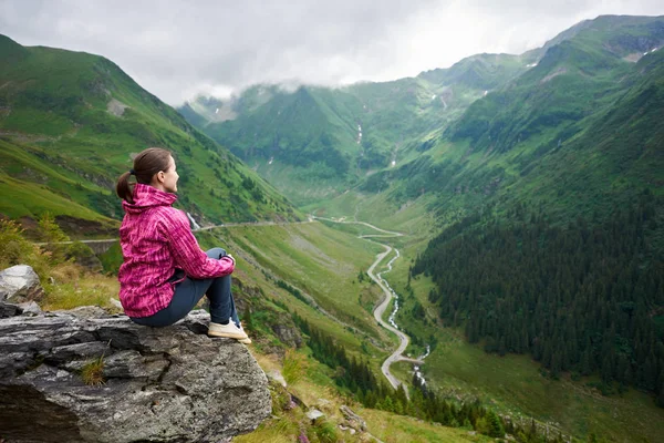 Знімок жіночого мандрівника, посміхаючись, дивлячись, сидячи на скелі, насолоджуючись настроюванням гірських пейзажів, що відпочивають після пішохідних копій ландшафтної природи, дружнього туризму подорожей . — стокове фото