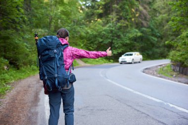 Dikiz kadın bir gezgin bir sırt çantası cathicng ile Taşıma Nakliye yaşam tarzı aktif keşfetmek backpacking turizm seyahat Bicaz Canyon yolu boşaltmak bir araba vurdu.