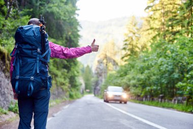 Gezgin kadın sırt çantası ile bir araba Bicaz vadide Cheile Bicazului-Hasmas Milli Parkı Romanya de yol yakalıyor