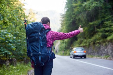 Sırt çantası ile kadın gezgin bir araba Bicaz vadide Cheile Bicazului-Hasmas Milli Parkı Romanya de yol yakalamak