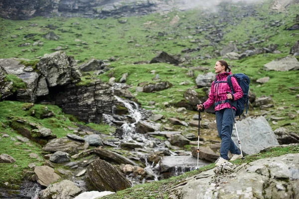 Young sportswoman hiking in the mountains with a backpack looking aroung copyspace observing enjoying recreation hobby leisure weekend active lifestyle camping nature exploring.