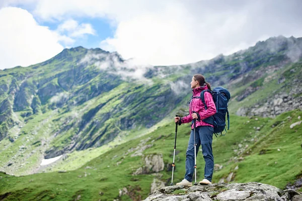 Backpacker kobieta odpoczynku podczas wędrówki w stojący na szczycie skały cieszyć się wspaniały widok na góry krajobraz wokół lato relaks odpoczynek camping wycieczkowicz hobby styl życia przyjemność przyrody. — Zdjęcie stockowe