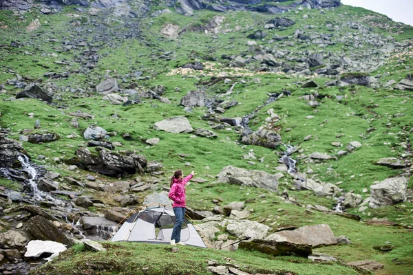 Turysta kobieta stojąc w pobliżu jej namiot w mountain valley wskazującego away miejsce explorer zwiedzanie podróżny podróży Turystyka rekreacja aktywny sportsmenka hobby natura koncepcja. — Zdjęcie stockowe