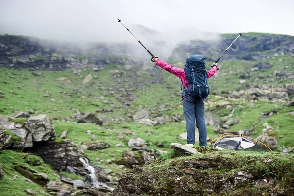 Visão traseira tiro de baixo ângulo de um caminhante feminino com uma mochila espalhando seus braços com postes de trekking em gesto de sucesso vitorioso copyspace natureza felicidade harmonia conquista liderança torismo . — Fotografia de Stock