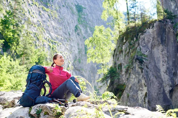 Zâmbitor turist de sex feminin odihnindu-se pe stâncă admirând frumusețea munților stâncoși uluitori într-un loc spectaculos din România. Femeie alpinist pozitiv fericit călătorie sănătoasă viață însorită zi iarbă deal vedere — Fotografie, imagine de stoc