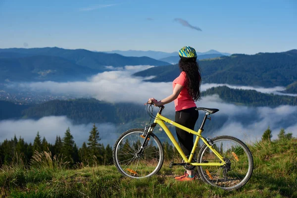 Женщина-велосипедистка с желтым велосипедом — стоковое фото