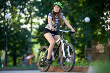 Genç kadın bisikletçi bisiklet sürme ve gelecekteki spor başarı ve olma sporcu yan düşünmeye seyir profesyonel bisiklet giyim.