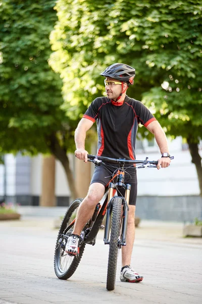 男子职业骑自行车穿着自行车的衣服和头盔站在自行车旁边 望边感兴趣和好奇 运动员在刻苦训练后有休息 健康生活方式概念 — 图库照片