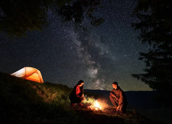 Pareja Joven Excursionistas Calentándose Alrededor Fogata Noche Acampando Cerca Del — Foto de Stock