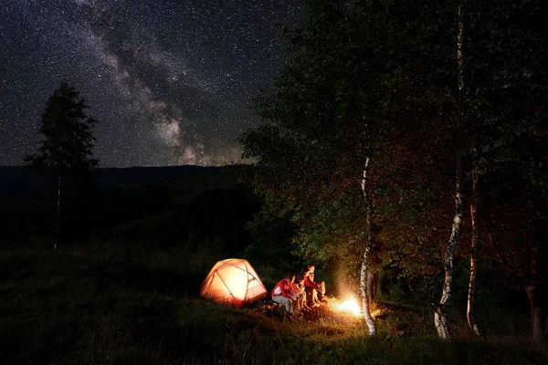 Cuatro Amigos Turistas Descansando Junto Fogata Sentados Troncos Durante Noche — Foto de Stock