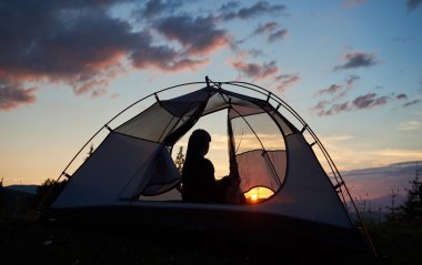 Yüce Dağları şafak parlak yükselen güneşin arka plan üzerinde zevk sabah mavi gökyüzünün altında bir çadırda oturan arka görünümü kız uzun yürüyüşe çıkan kimse. Bir çadır görüntülemek