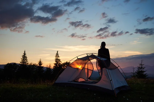 女の子の背面ビュー シルエットでは 山の頂上にキャンプ付近の夜明けをお楽しみください 朝の光の美しい自然 モミの木 明るい上昇と強力な山の太陽し 光雲の空 — ストック写真