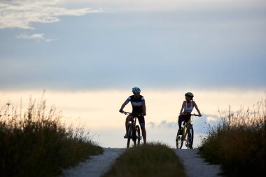 Çift birbirlerine arka planda bir ufuk ile güzel bir akşam gökyüzü izlerken bir ülke yolda bisiklet üzerinde oturan Bisiklet. 