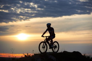 Sağlam ve güçlü bir adam spor giyim ve bisikletiyle oturan ve tepede poz kask giyiyor. Harika gün batımı manzarasına zevk bisikletçi. Kavramı motivasyon, rekreasyon ve sağlıklı faaliyetleri.