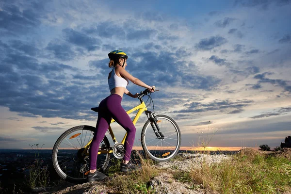 运动的女孩站在自行车旁边 在山上摆姿势 穿着紫色紧身裤和白色顶部的苗条漂亮女人 — 图库照片