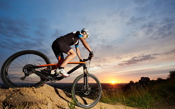 在头盔和运动的自行车橙色自行车的精力充沛和活跃的人的看法 运动和精力充沛的运动员在日落时骑马下山 — 图库照片
