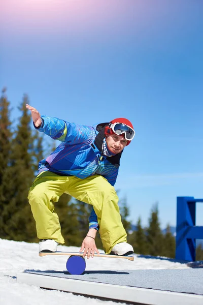 在阳光明媚的冬日 戴着护目镜和头盔的雪地人骑着雪板 在陡峭的雪山斜坡上飞驰而下 背景是蓝天和云杉 — 图库照片
