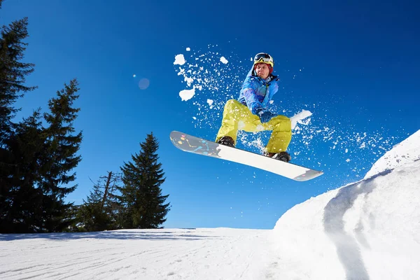 在阳光明媚的冬日 戴着护目镜和头盔的雪地人骑着雪板 在陡峭的雪山斜坡上飞驰而下 背景是蓝天和云杉 — 图库照片