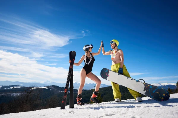 穿着比基尼的性感女人和赤身裸体的雪人在雪山滑雪板上笑着 — 图库照片