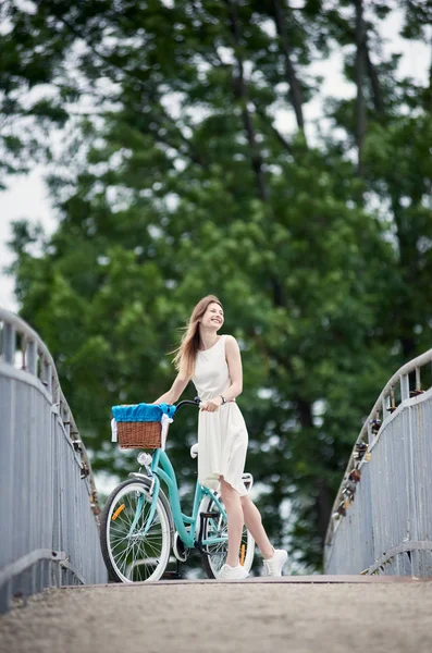 Νεαρό Κορίτσι Ένα Λευκό Φόρεμα Στέκεται Στη Γέφυρα Μπλε Ποδήλατο — Φωτογραφία Αρχείου