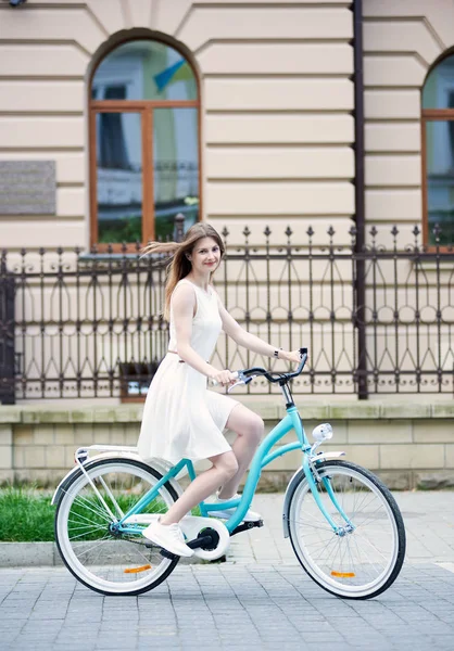 美しいです女の子でライトドレスとスニーカー上の青レトロバイクで古い建物の背景 — ストック写真