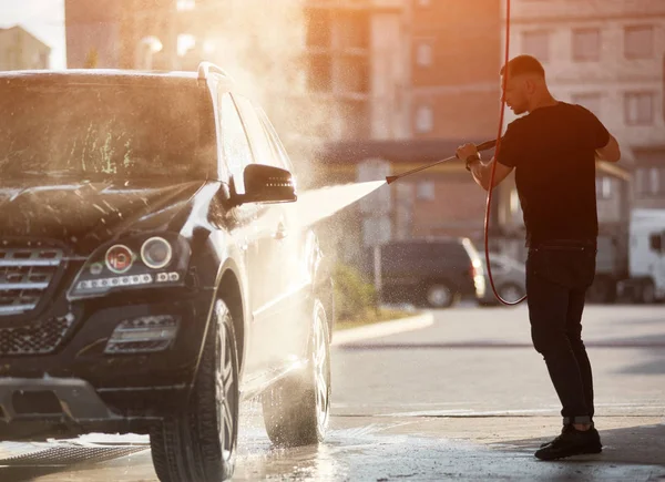 Silhueta Homem Forte Segurando Uma Mangueira Lavando Seu Carro Preto — Fotografia de Stock