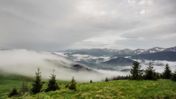山の中を流れる雲を眺めながら山の上をタイムラプス 山は緑の火で覆われ 時々曇りの日に雪が降る — ストック動画