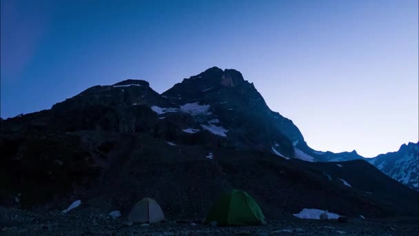在山中的一座帐篷城市里 时间已经消逝了 两个帐篷矗立在一块巨大的岩石下面 太阳在蓝天下开始照耀着这块岩石 美丽的山景 — 图库视频影像