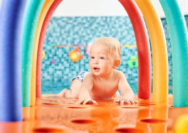 Çok tatlı bir çocuk yüzme havuzunda yüzen renkli bir yapının üzerinde göbeğinin üstünde yatıyor. Sağlıklı çocukluk kavramı