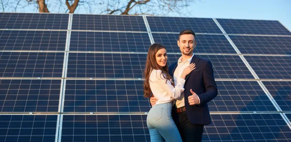 Dos Jóvenes Paran Abrazándose Fondo Los Paneles Solares Miran Cámara — Foto de Stock