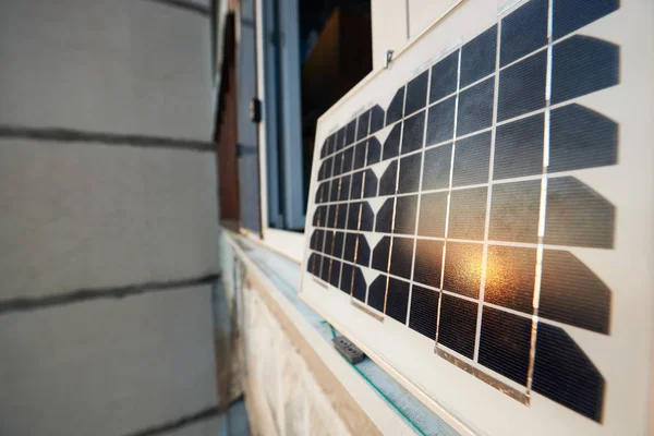Close-up of a solar panel standing on a window of a high-rise building and reflects the sun at sunset. Concept converting solar radiation into electricity