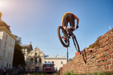 Amatör bisiklet numarasının arka planı. Şehir merkezindeki atlet, dağ bisikletinde atlama pratiği yapan mimarinin arka planında. Spor hayatı kavramı.