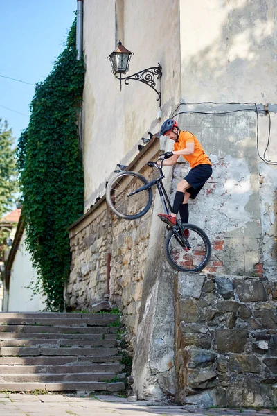 Side view of a stuntman getting ready to jump with his mountain bike from the corner of ancient building