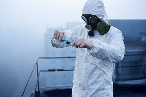 Scientific research on a subject dangerous environment, conducted by a laboratory worker in protective suit on roof of building, holding appropriate equipment