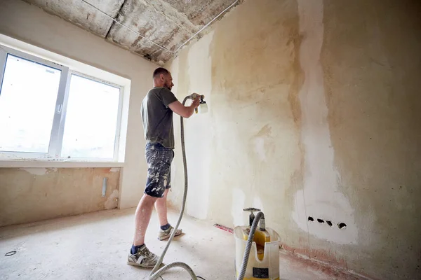 Homem Pintando Uma Parede Cinza Com Pistola Pulverização Renovação Casa — Fotografia de Stock