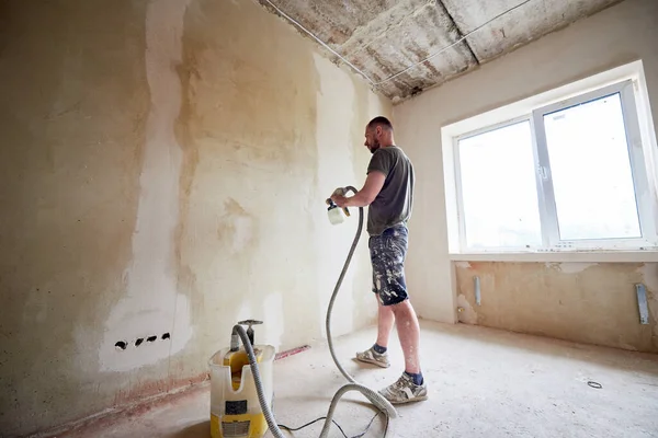 Vista Lateral Homem Pintando Uma Parede Cinza Com Pistola Pulverização — Fotografia de Stock