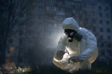 Çömelmiş bir bilim adamı, laboratuvar aletleri ve sıvılarla yeni numunelerle gezegenimizi kurtarma kavramını kullanarak dışarıda çalışıyor.