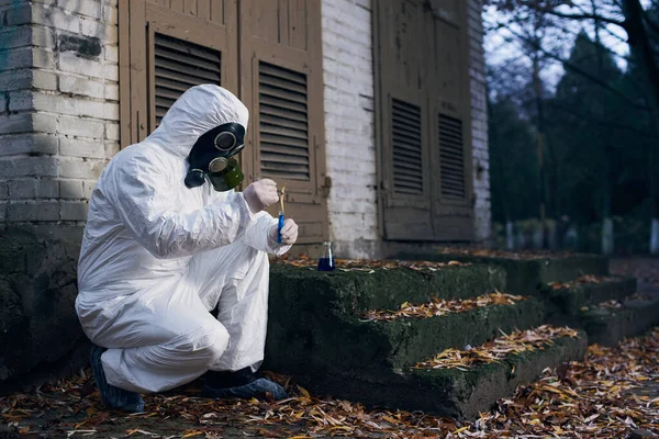 保護カバー ガスマスクと手袋を身に着けている科学者 ガラスフラスコとローカルサンプルを使用して専門知識を作る労働者 コピースペース — ストック写真
