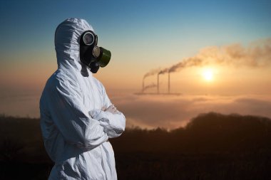 Erkek çevrecinin yan görünüşü çapraz kolları yana bakarken termal bacalar zehirli gazlarla atmosfere duman yayıyor. Beyaz radyasyon kıyafeti ve gaz maskesi giyen bir ekolojist..