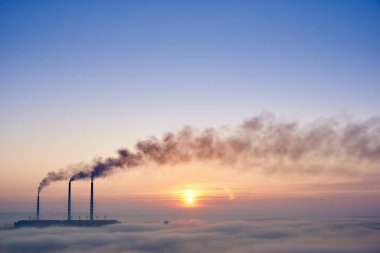 Ufukta üç tüten termal güç santralinin yatay görüntüsü görünüyor.