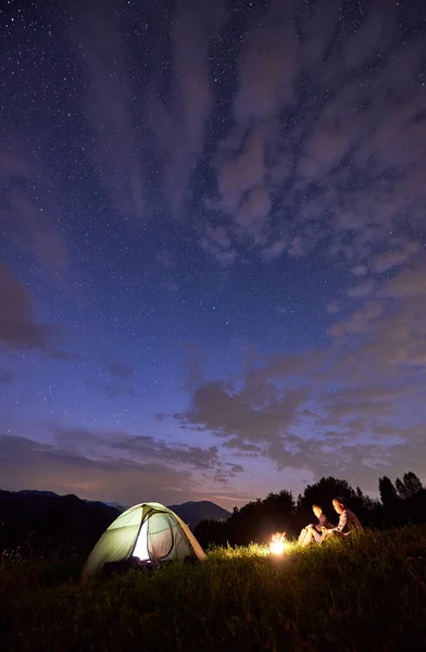 텐트와 별들이 아름다운 아래서 모닥불 근처에서 저녁에 산에서 시간을 보내는 — 스톡 사진