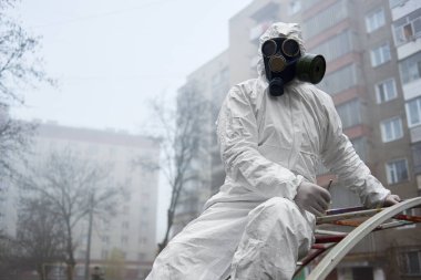 Koruyucu üniformalı erkek çevreci sokak sporları sahasında dinlenirken elinde cımbız tutuyor.. 