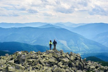 Arka plan turistlerin el ele tutuşması ve güçlü manzaranın tadını çıkarması. Erkek ve kadın, gökyüzünün altındaki uçurumun tepesinde kümülüs bulutlarıyla dikiliyorlar.