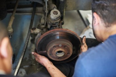 Otomobil tekerlerinin diskini tutan erkeklerin ellerini kapatın. Garajda yeni lastik değiştirme işleminde olan bir adam araba tekerleğiyle ilgileniyor. Otomatik servis kavramı.