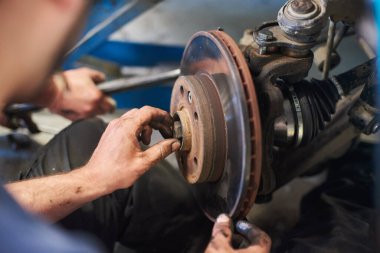 Erkek kirli ellerin merkezi delikten cıvatalanması. Garajda yeni lastik değiştirme işleminde olan araba tekerleğinin vidalarını söken beyefendi. Otomatik servis kavramı.