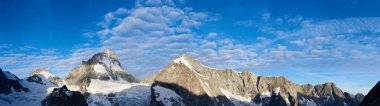 İsviçre 'nin Dent Blanche Alplerinde yeni bir gün, sabah güneşi kayalık dağların sırtında parlarken, vadi hala karanlıktayken, panoramik çekim