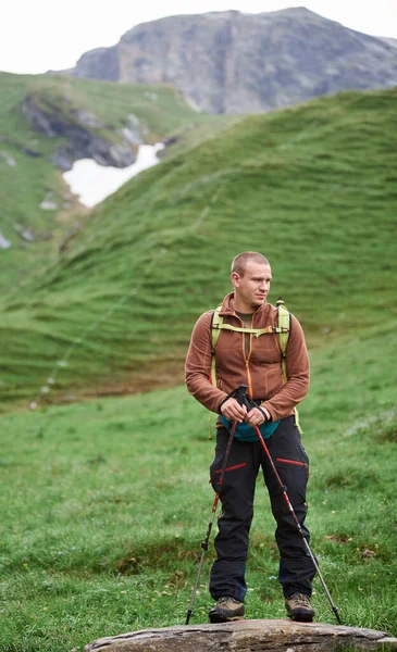 男ハイカーのトレッキングポールを保持し 脇を見ての完全な長さ 旅行者の山の谷の石の上に背景がぼやけて草の丘に立っている ハイキング 観光の概念 — ストック写真