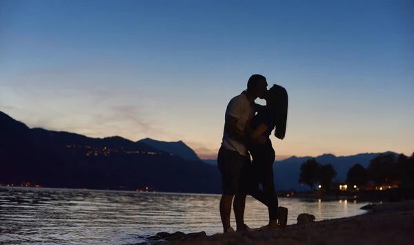 在美丽的落日下 轮廓上的一对年轻夫妇在海滩上拥抱和亲吻 男朋友和女朋友在海边共度柔情时光 浪漫和关系的概念 — 图库照片