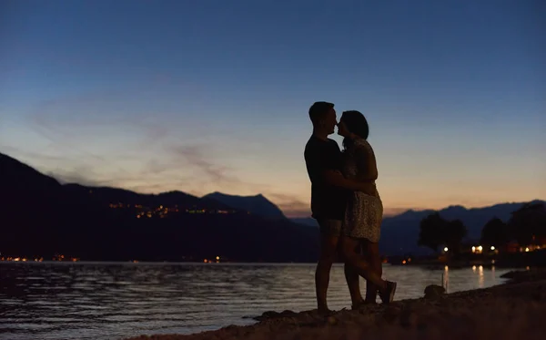 美丽的落日下 一对快乐的年轻夫妇在海滩上拥抱和触摸着鼻子的轮廓 男人和女人在海边分享着温柔的时刻 浪漫和关系的概念 — 图库照片