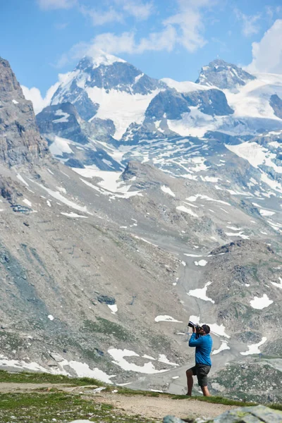 Мужчина Фотографирует Величественные Скалистые Горы Профессиональной Камерой Турист Стоящий Склоне — стоковое фото
